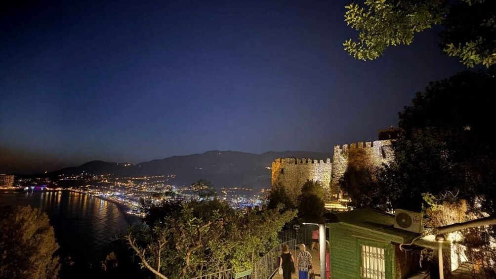 A nighttime view of a historic castle overlooking a city with a river. 4