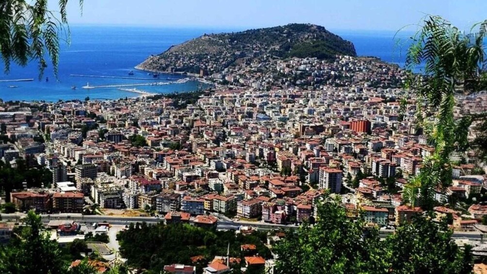 A coastal cityscape with dense urban buildings, a prominent hill with a small settlement, and the sea in the background. 3