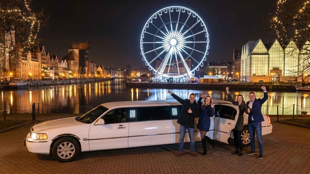 A white limousine parked by a river with a large illuminated Ferris wheel in the background. 5