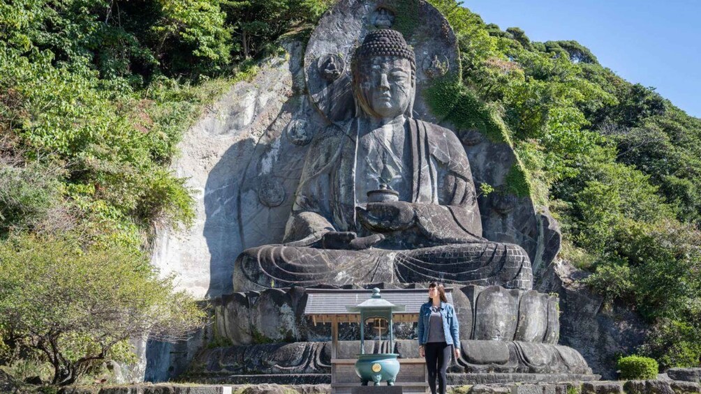 A large seated Buddha statue with a bell and incense burner in front, surrounded by lush greenery. 2