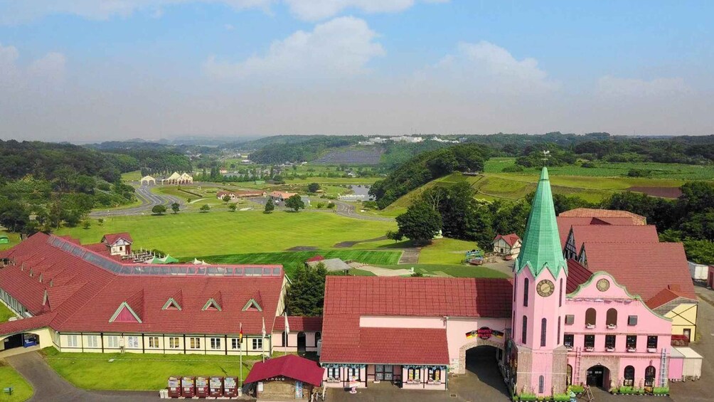 A town with a prominent church, a red-roofed building, and green fields. 4