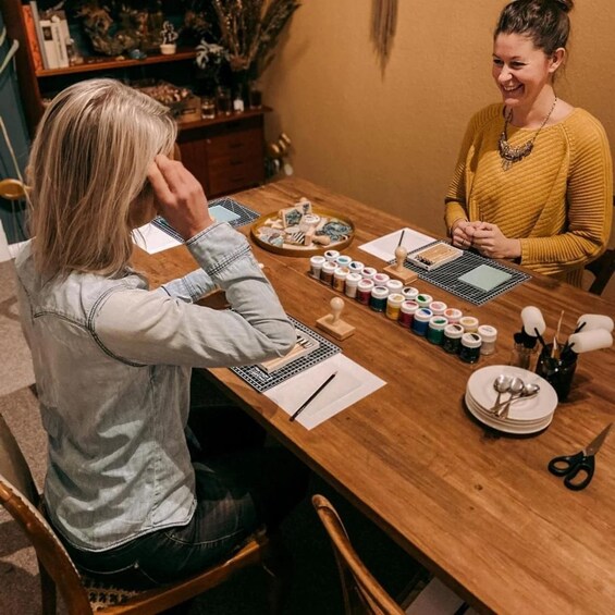 Two people at a table with art supplies, including paint and brushes. 2