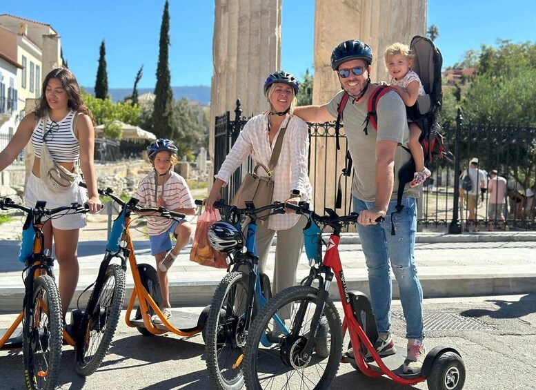 A family with bicycles and a tricycle in a public square with historical architecture. 5
