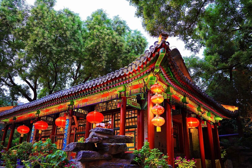 A traditional Chinese building with ornate architecture, red lanterns, and a stone fountain. 5