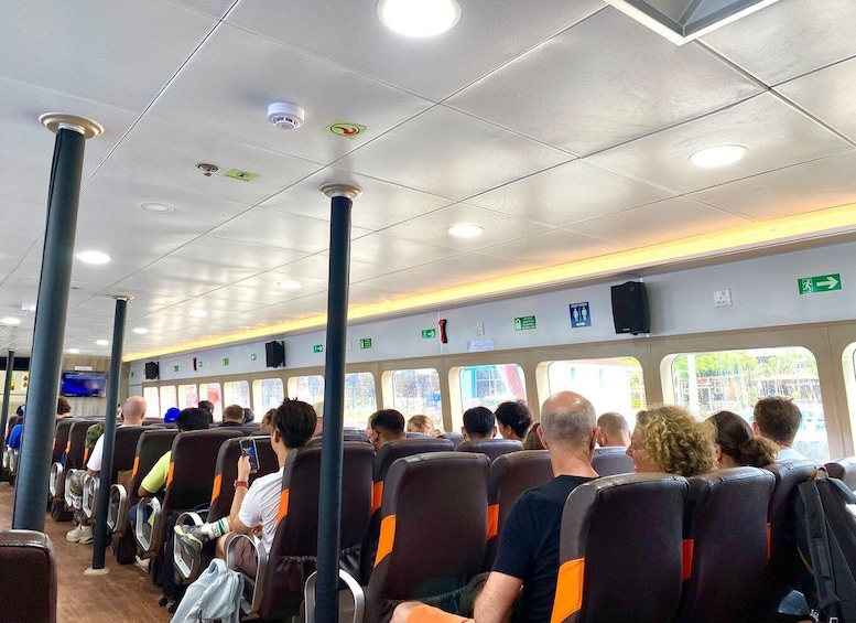 A train interior with passengers seated, overhead compartments, and emergency exit signs. 5
