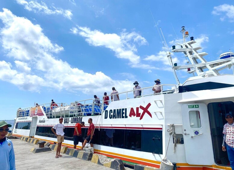 A ferry with 'BALI - LOMBOK' written on it, passengers boarding, and a clear blue sky. 2