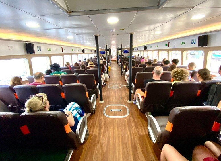 A ferry interior with rows of seats, windows, and overhead compartments. 1