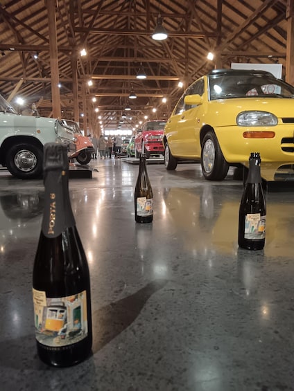 Vintage cars and bottles of wine in a covered indoor space. 4