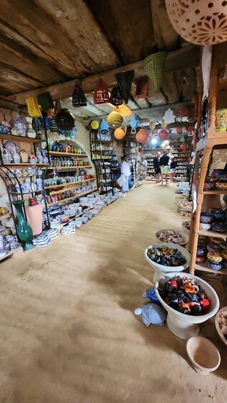 A pottery shop with shelves of colorful ceramics and hanging lanterns. 2