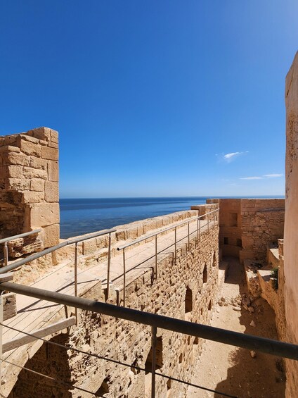Ancient stone ruins with a metal railing overlooking the sea. 3