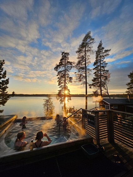 A hot tub area with a sunset view, surrounded by trees and a calm lake. 4