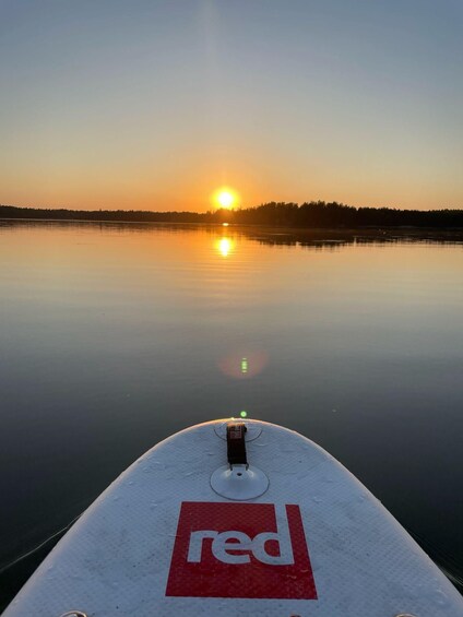 A calm lake at sunset with a boat in the foreground and a forest in the background. 2