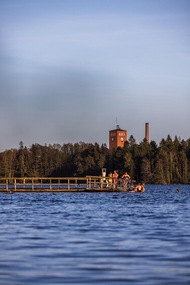 A pier with people, a clock tower, and a smokestack in the background. 3