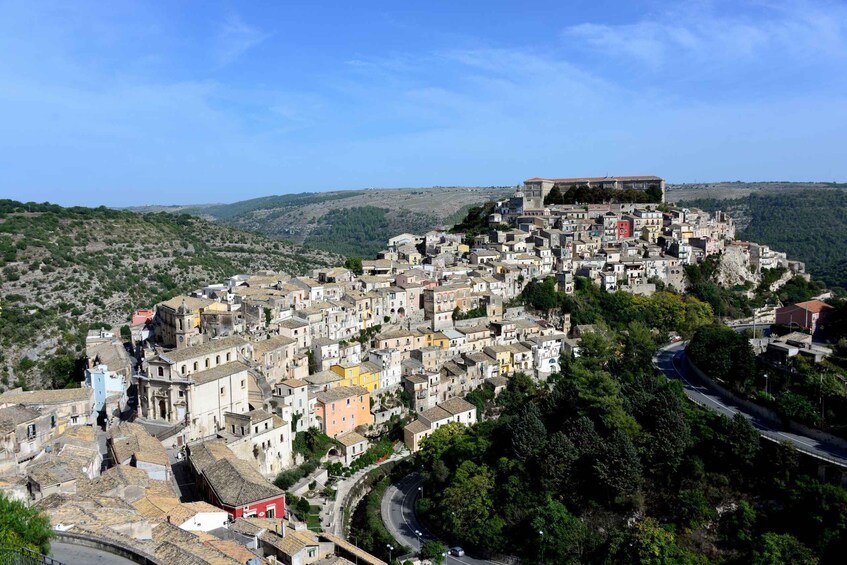 A hillside town with historic buildings, a prominent church, and a road curving through the landscape. 1