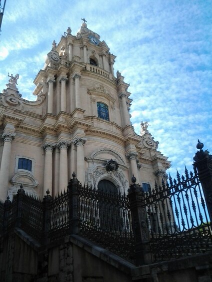 A historic building with ornate architecture, including a clock tower and statues. 3