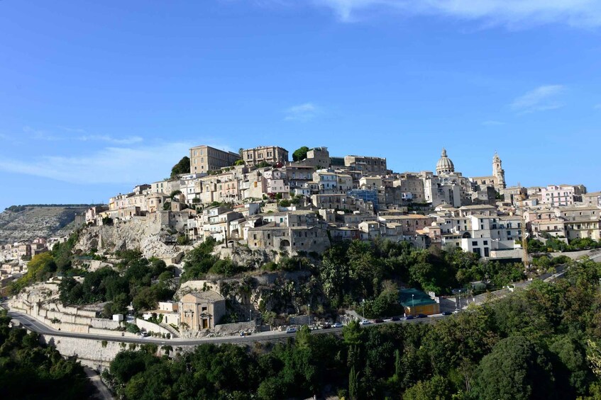 A densely packed hillside town with historic architecture, including a prominent church with a dome and bell tower. 2