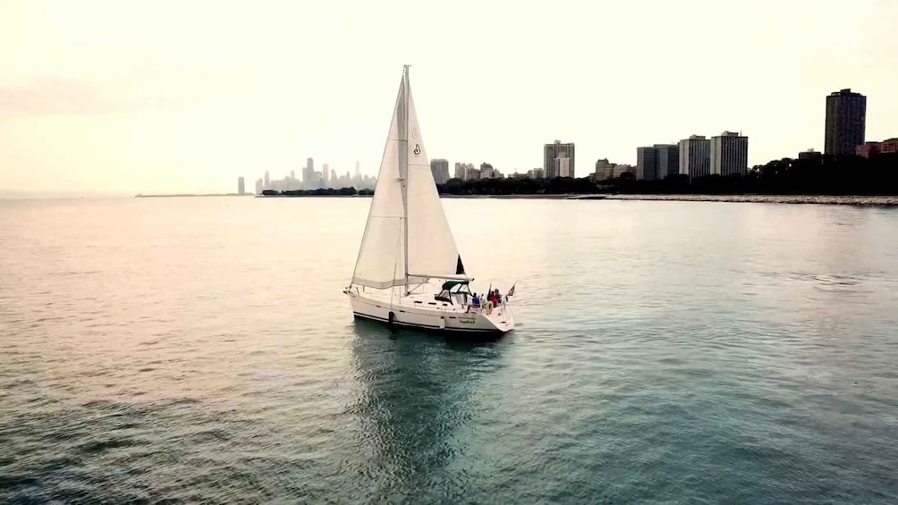 A sailboat on calm waters with a city skyline in the background. 2
