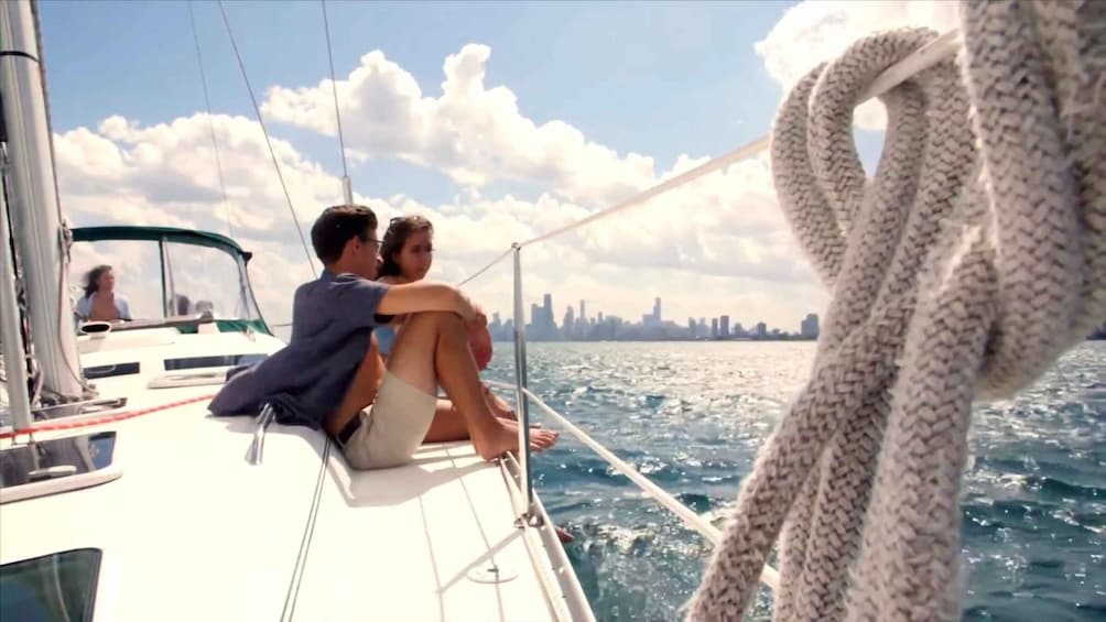 A couple on a sailboat with a city skyline in the background. 1