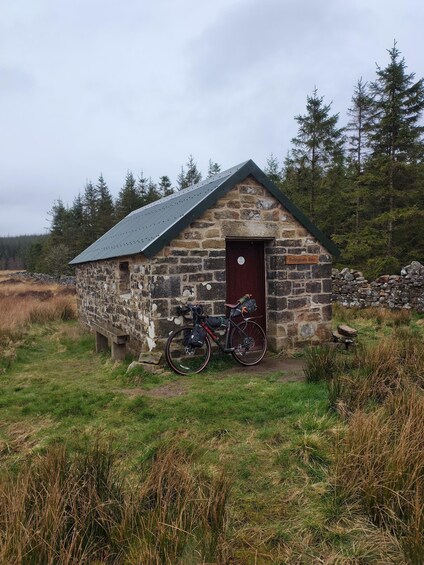 A stone building with a metal roof, a bicycle parked in front, and a sign reading 'Bellingburn Barn.' 3