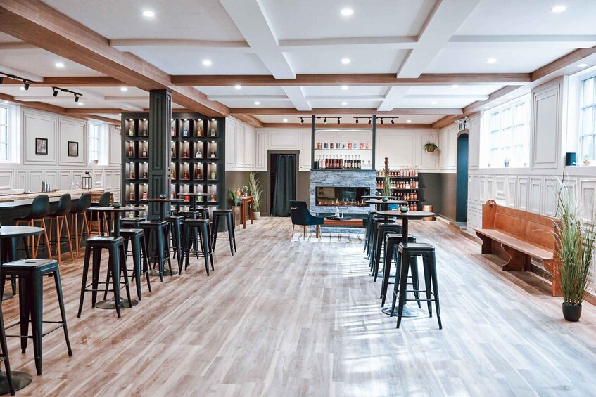 A spacious bar area with wooden floors, black bar stools, and a central seating area with a bench. 1