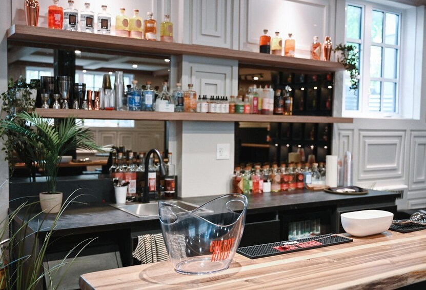 A bar with shelves of liquor bottles, a clear glass pitcher, and a wooden counter. 2