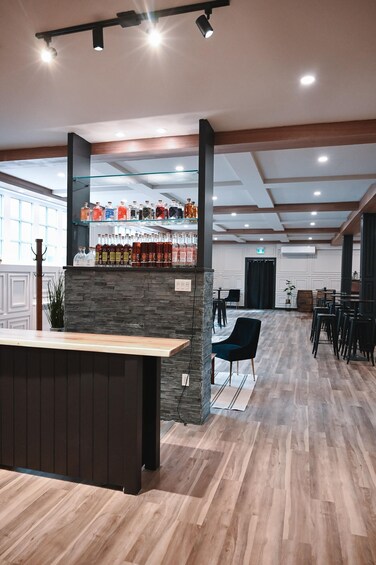 A bar area with a wooden counter, stone wall, and shelves of liquor bottles. 5
