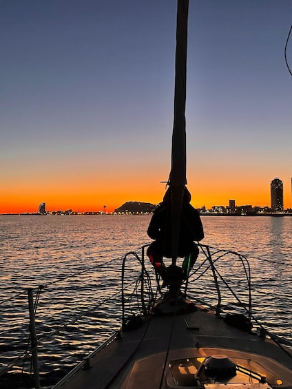 A person sitting on a boat with a city skyline in the background during sunset. 1
