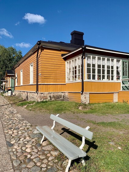A wooden building with a green door, a stone pathway, and a bench. 1