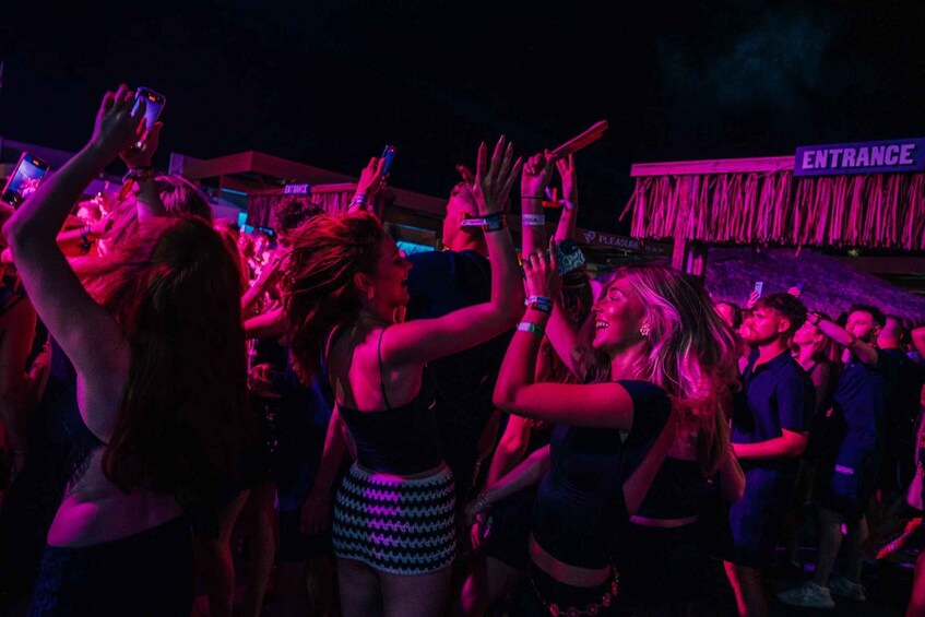 A crowded indoor event with people holding up their phones, likely taking photos or videos. 1
