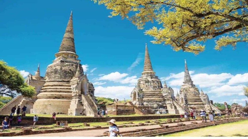 Ancient stone structures with multiple tiers and pointed spires, surrounded by a clear blue sky and lush greenery. 2