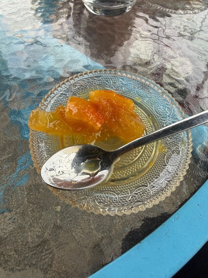 A spoonful of orange marmalade on a glass plate with a blue rim. 1