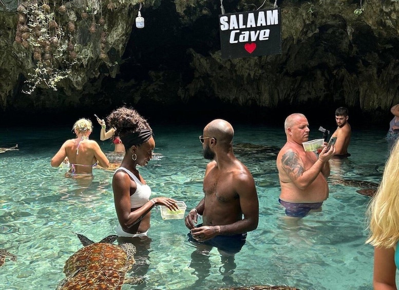 A group of people in a natural pool with a sign reading 'Salah Cave.' 4