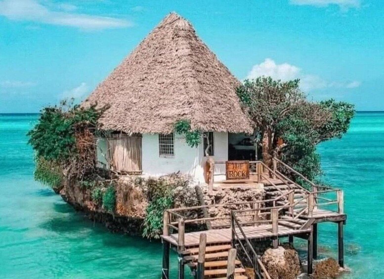A thatched-roof hut on a small island with a wooden dock. 5
