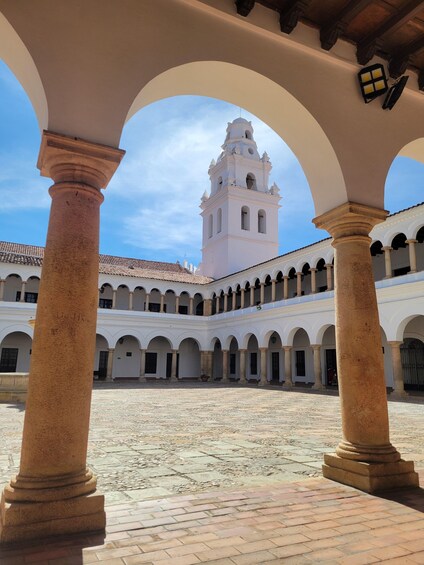 A courtyard with white columns and a bell tower. 2