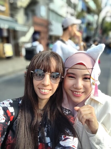 Two people taking a selfie with a street and buildings in the background. 3