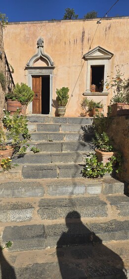 A set of stone steps leading to a building with a wooden door and a window with a pediment. 1