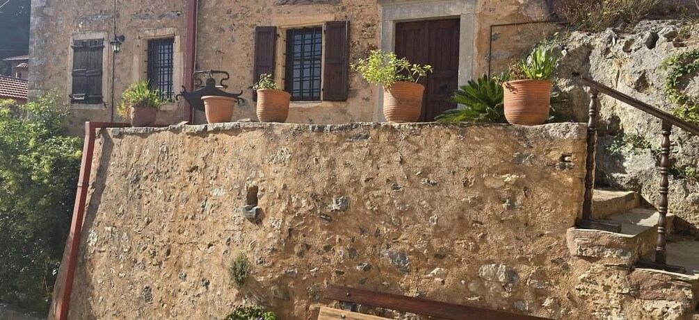 A stone wall with potted plants and a wooden staircase. 5