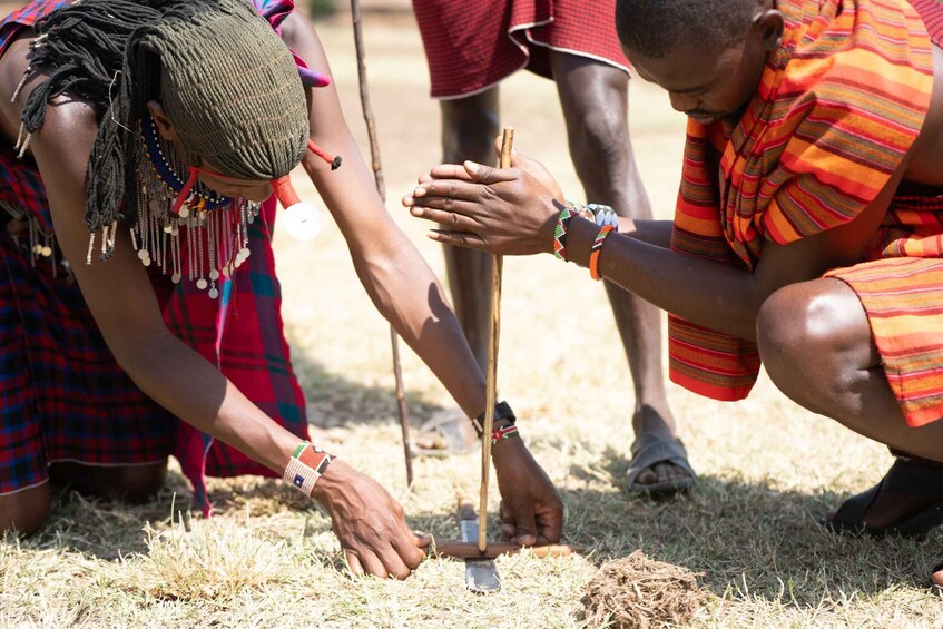 People engaged in an outdoor activity, possibly related to agriculture or craft, in a natural setting with dry grass on the ground. 1
