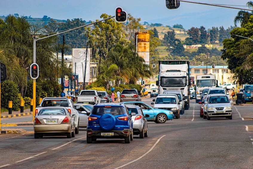 A busy urban street with multiple lanes of traffic, including cars and trucks, and a traffic light ahead. 2