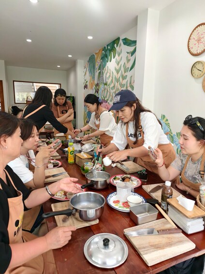 A group of people gathered around a table, preparing food. 1