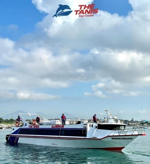 A boat named 'The Tanis' with people on deck, docked at a marina with mountains in the background. 2