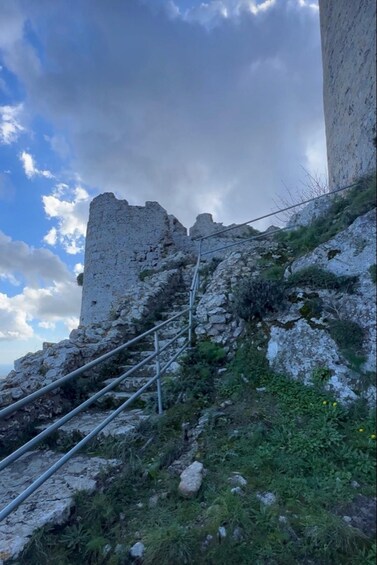 A rocky hill with a dilapidated tower and metal stairs leading up to it. 4