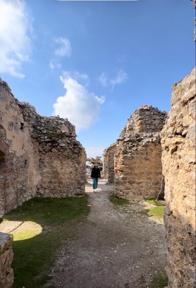 A pathway through ancient stone ruins with a clear sky above. 2
