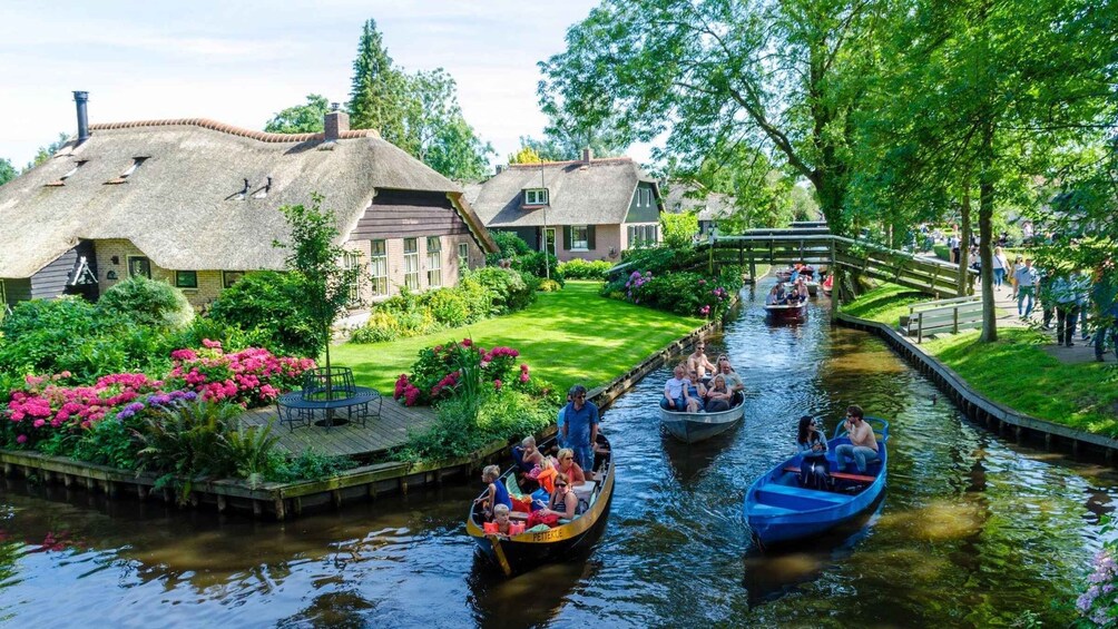 A canal with boats, a bridge, and houses with thatched roofs. 1