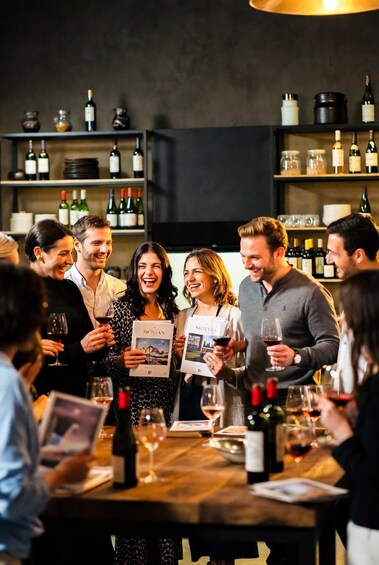 A group of people at a wine tasting event, holding wine glasses and brochures. 3