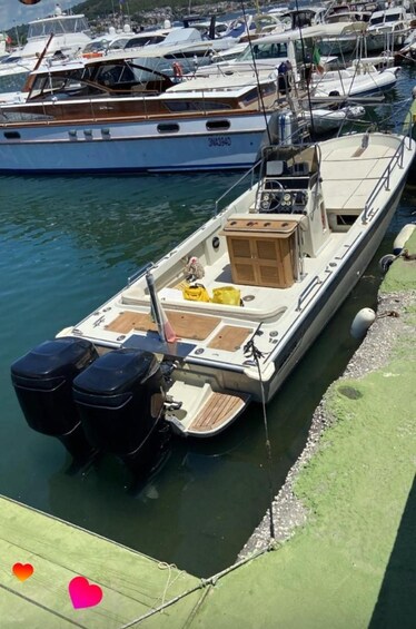 A small motorboat docked at a marina with other boats in the background. 2