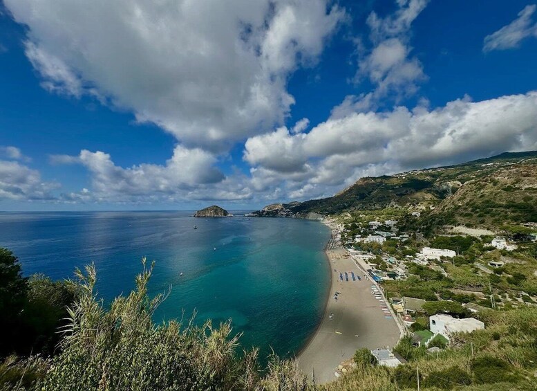 A coastal landscape with a clear blue sea, a sandy beach, and a small island in the distance. 1