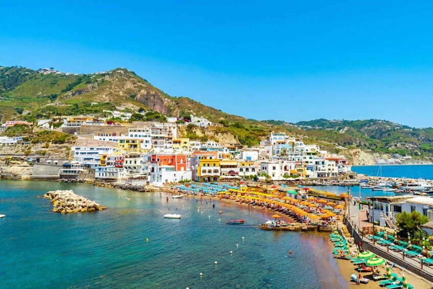 A coastal town with colorful buildings, a beach with umbrellas, and boats in the water. 4