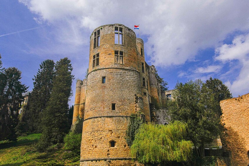 A historic stone tower with a flag, surrounded by trees and a clear sky. 5