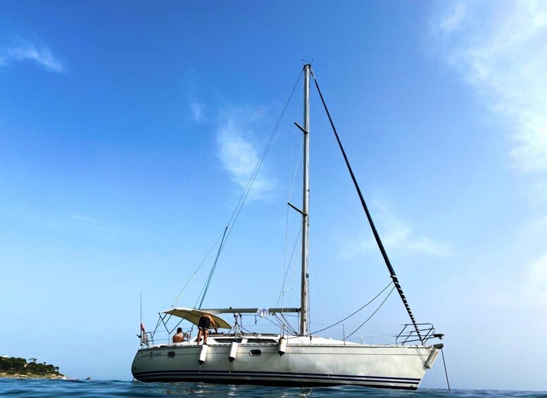 A sailboat with a tall mast and rigging, anchored in calm waters with a clear sky. 5